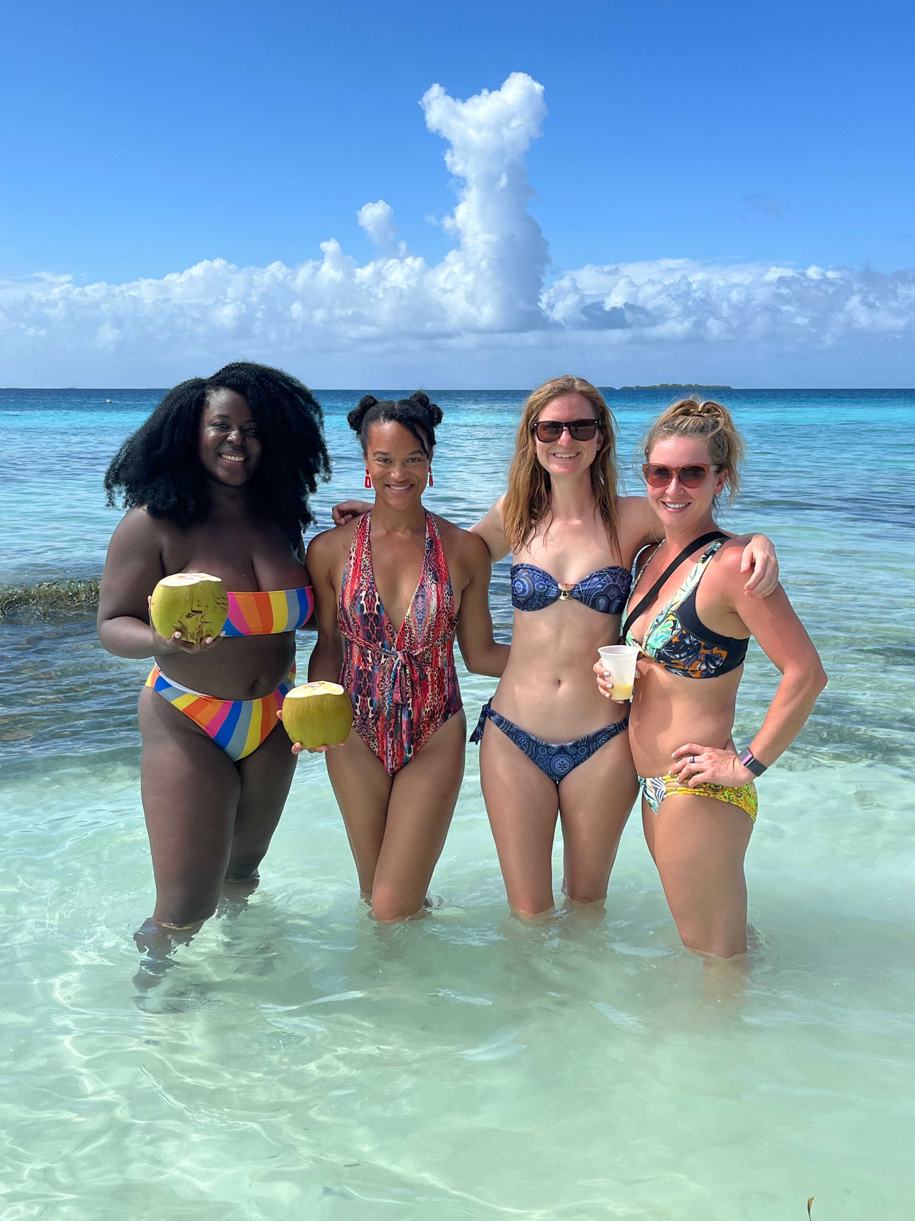 Four women in crystal-clear shallow ocean water