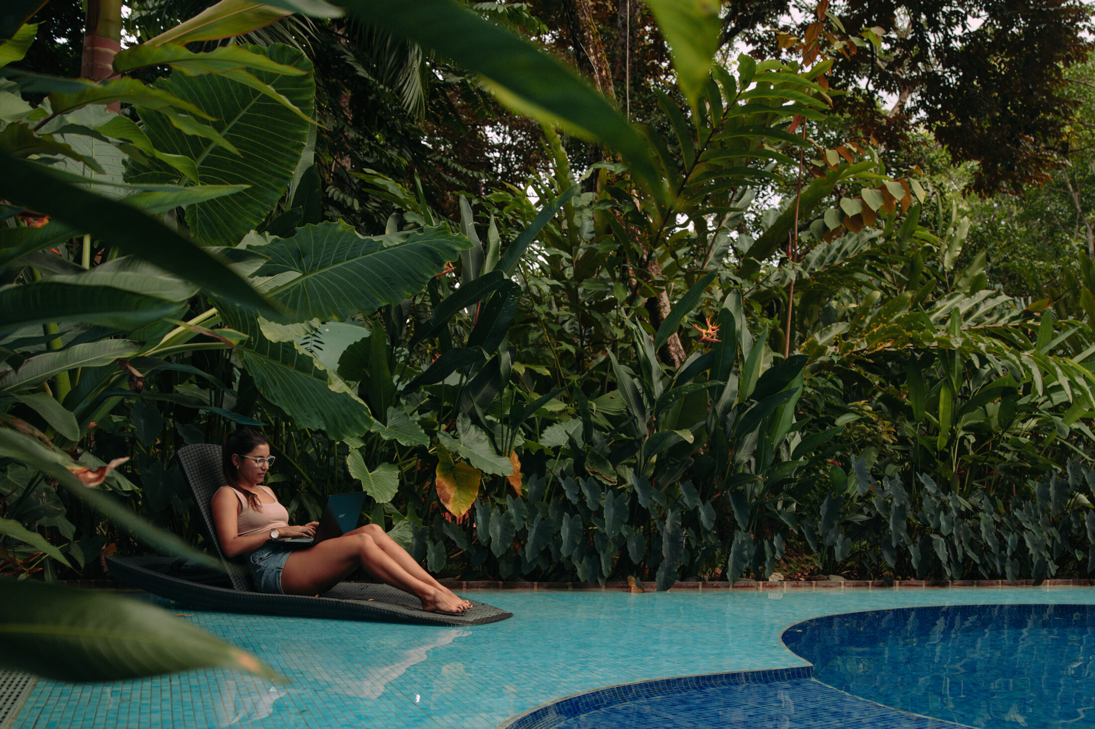 Noma member working on a laptop by a jungle poolside