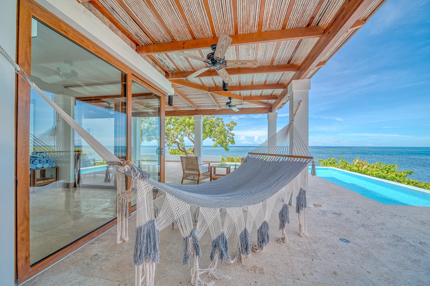 A villa terrace with a hammock, infinity pool and ocean view at Próspera
